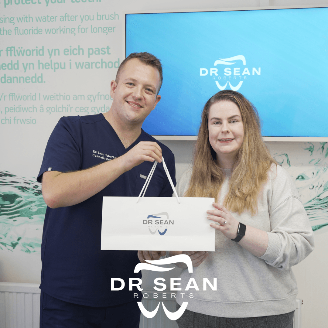 Dr Sean Roberts handing a gift bag to a smiling patient at Friars Dental Clinic in Aberystwyth