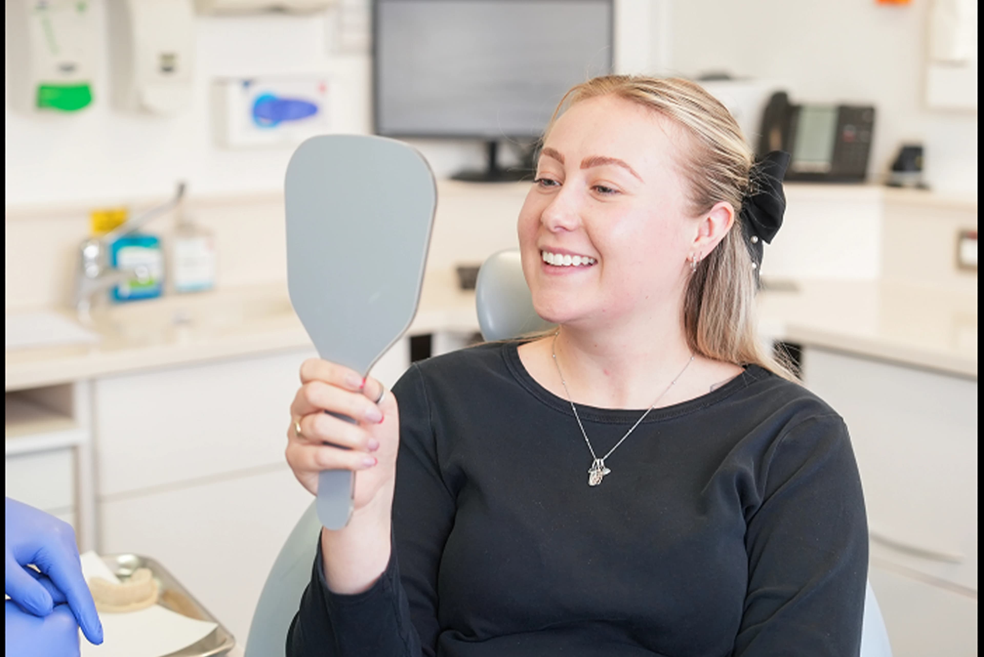 Patient smiling while viewing her teeth in a mirror at Dr Sean Roberts' dental practice