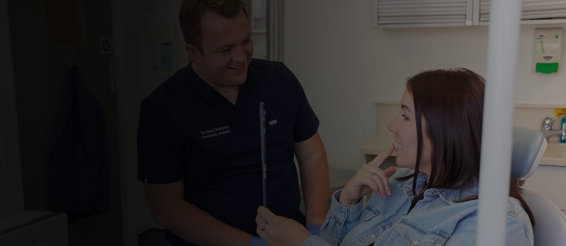 Dr Sean Roberts discussing dental treatment options with a patient holding a mirror